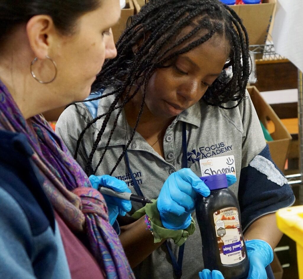 Participant in a Focus employment training program receives hands-on instruction while holding a bottle.