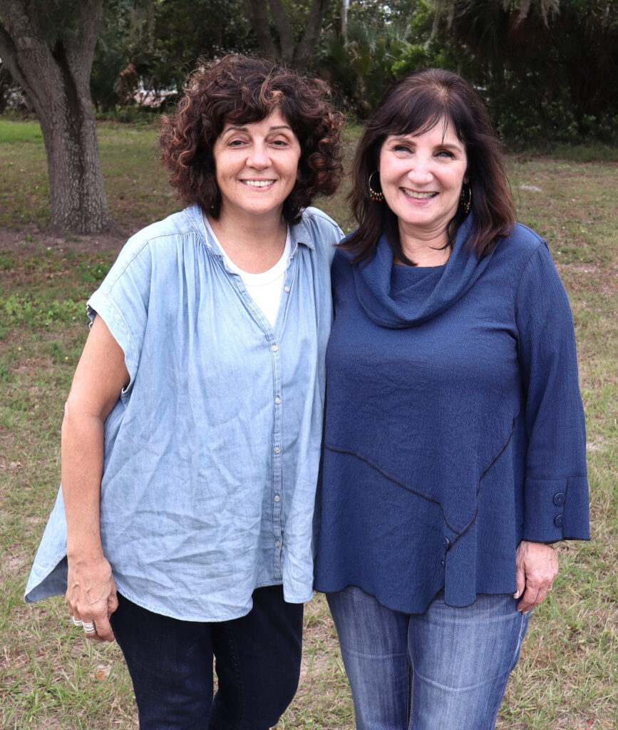 Two women standing together outdoors and smiling at the camera