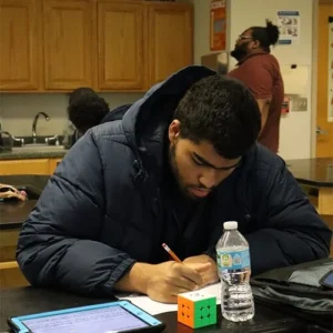 Focus Academy student writing notes at a desk during a classroom research project.