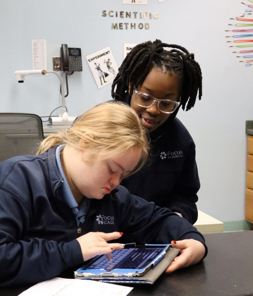 Two Focus Academy students using a tablet together during a classroom research project.
