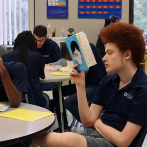 Student in a classroom reading the book Wonder during a Focus Academy lesson.