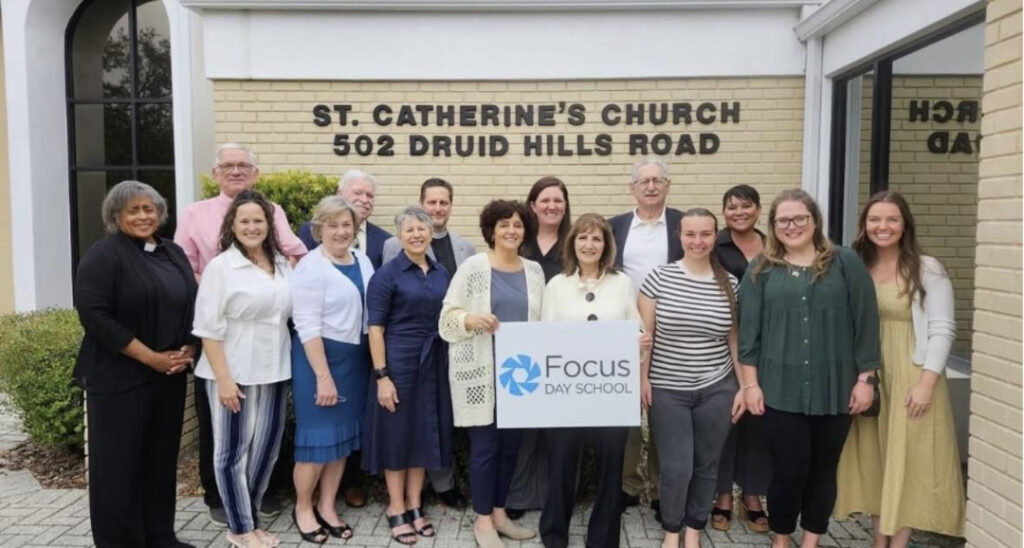 Group standing outside St. Catherine’s Church holding a Focus Day School sign.