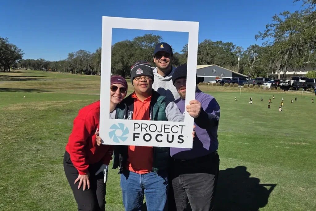 Two golfers holding the Project Focus frame on the course