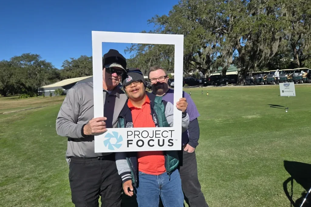 Three golfers with the Project Focus photo frame