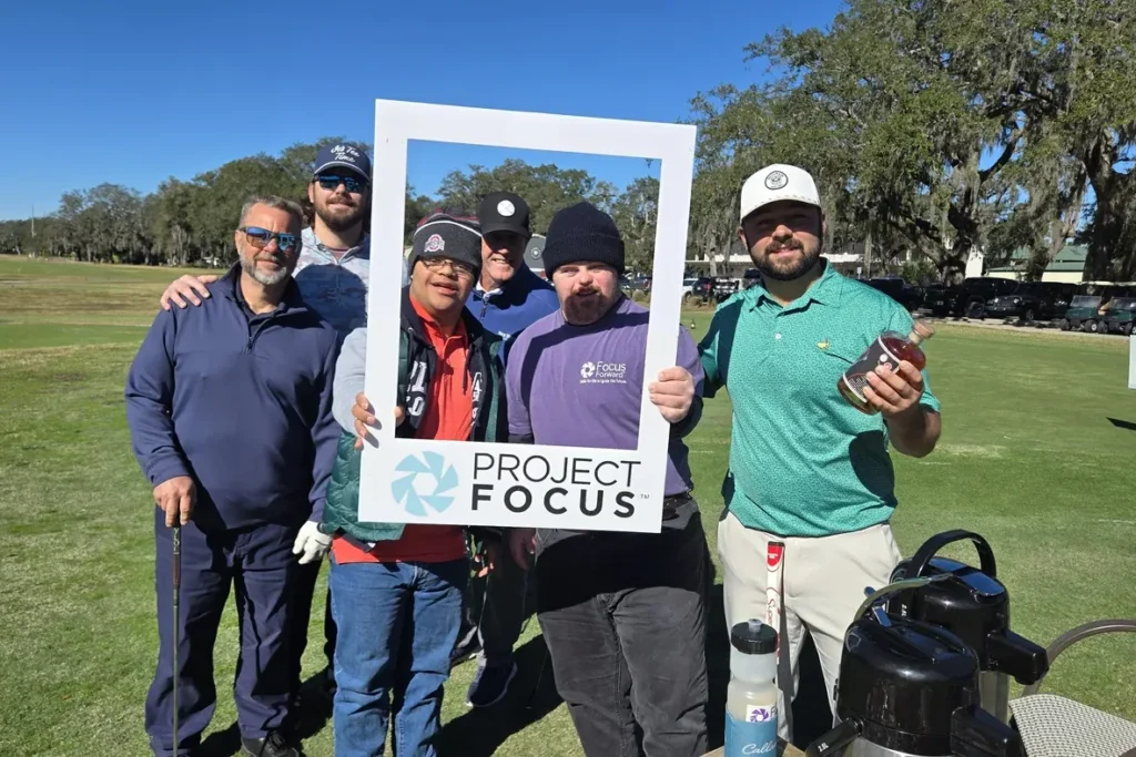 Golfers holding a Project Focus photo frame on the course