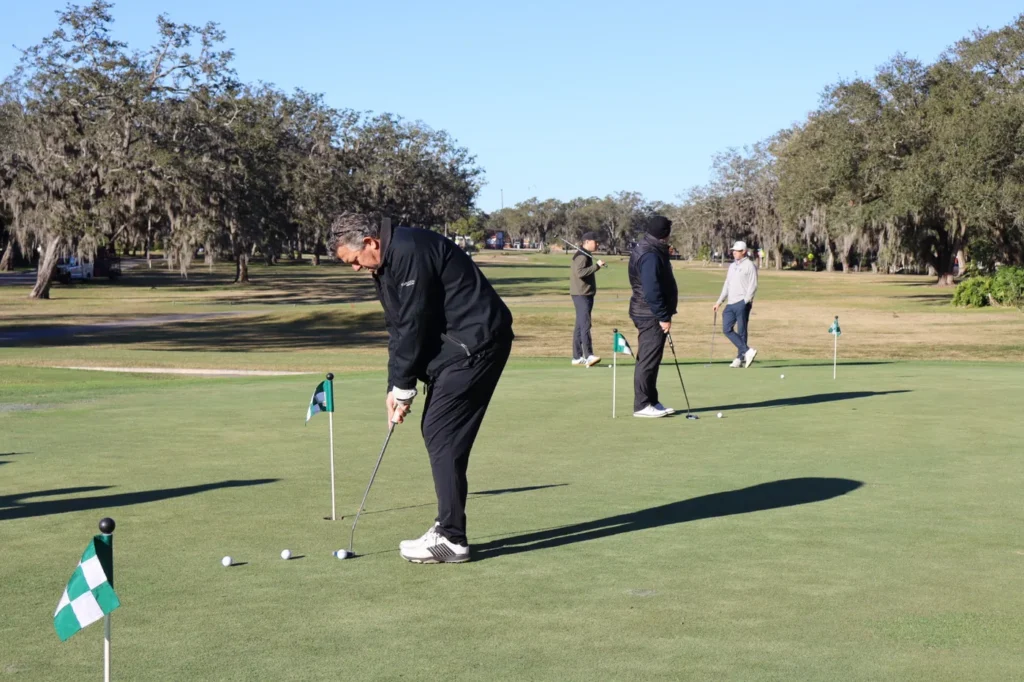 Golfers putting on the green under the oaks