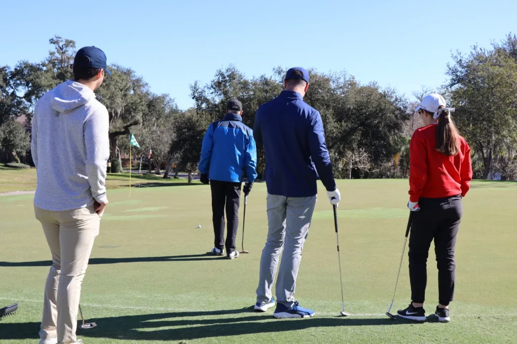 Golfers walking onto the green with clubs